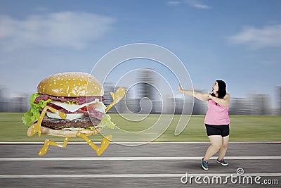 Fat woman escaping from a burger Stock Photo