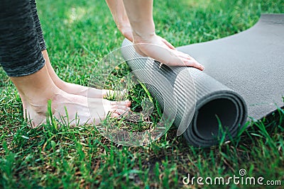 A picture of female`s legs and hands. Girl is rolling up the carimate. Close up. Yoga and Pilates Concept. Stock Photo