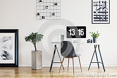 Picture gallery and a concrete planter in a simple home office interior for a freelancer professional with a computer screen mock- Stock Photo