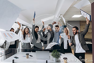 Picture of happy business team celebrating victory in office. Successful business team throws pieces of paper in modern office Stock Photo