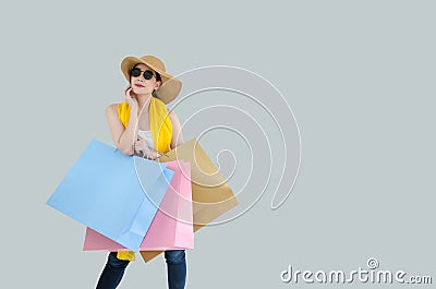 Picture of a happy young chinese woman in white summer undershirt, scarf and jeans wearing sunglasses posing with shopping bags Stock Photo