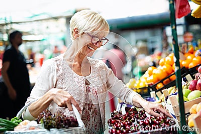 Picture of mature woman at marketplace buying vegetables Stock Photo