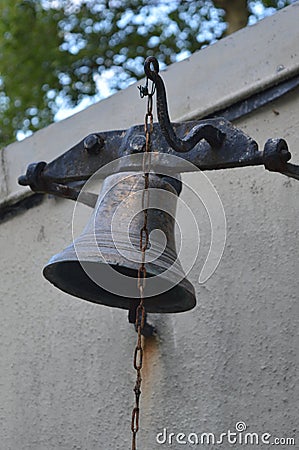 An old rusty iron bell hanging on the wall of the house Stock Photo
