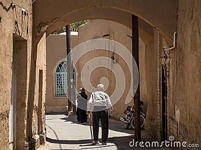 Iranian seniors, one old man and one old woman, walking in one of the streets of the old town of Yazd Editorial Stock Photo