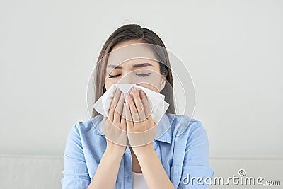 Picture of a sick young lady sitting on the couch and blowing he Stock Photo