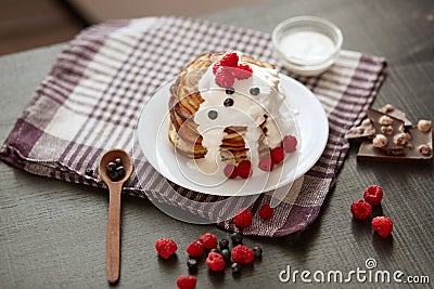 Picture of stack of pancakes with blueberries and raspberries on white plate, dark brown colour r backdrop decorated with cup of Stock Photo