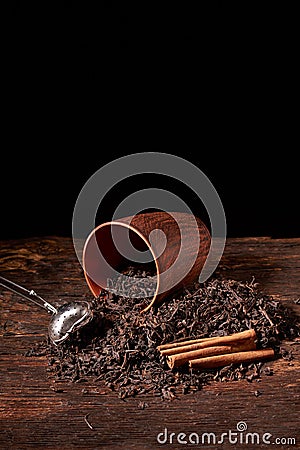 Picture of the tea strainer with dried tea leaves and sticks of cinnamon isolated on dark wooden background Stock Photo