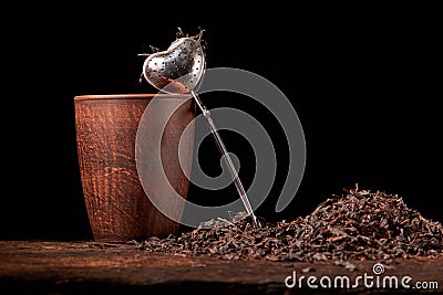 Picture of the tea strainer with dried tea leaves and sticks of cinnamon isolated on dark wooden background Stock Photo