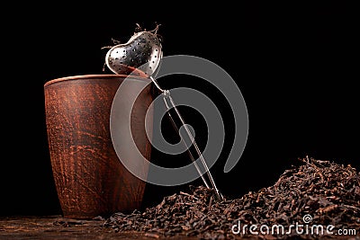 Picture of the tea strainer with dried tea leaves and sticks of cinnamon isolated on dark wooden background Stock Photo