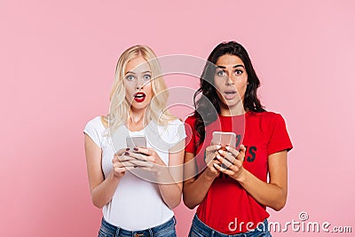 Picture of Two pretty shocked women holding smartphones Stock Photo