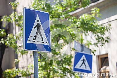 Two roadsigns warning drivers of the presence of a crosswalk with pedestrians crossing in an urban landscape Stock Photo