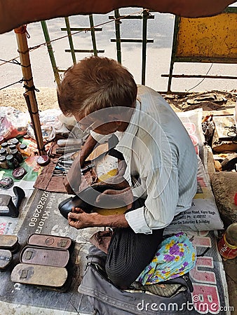 An unknown Shoe Cobler Repairing a Pair of Shoes at Indian Street. Editorial Stock Photo