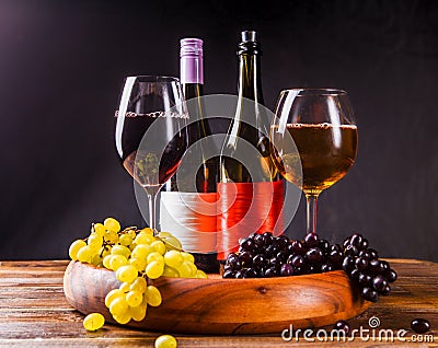 Picture of wine glass with wine, grapes black, green on wooden tray on table Stock Photo