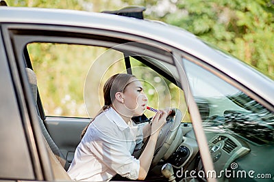 Picture of young businesswoman speaks by phone and doing makeup while driving a car in the traffic jam Stock Photo