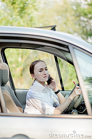 Picture of young businesswoman speaks by phone and doing makeup while driving a car in the traffic jam Stock Photo