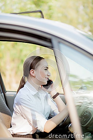 Picture of young businesswoman speaks by phone and doing makeup while driving a car in the traffic jam Stock Photo