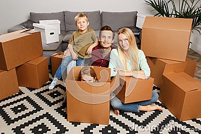 Picture of young couple with son and daughter sitting on floor among cardboard boxes Stock Photo