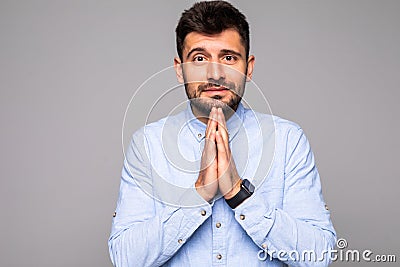 Picture of young guy dressed casually having put hands together in prayer or meditation, looking relaxed and calm, dreaming and Stock Photo