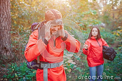 Picture of young man holding hands on head. He has headache. Young woman stands behind him and reaches with hand. Stock Photo