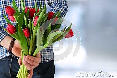 Picture of young man surprising woman with flowers. Stock Photo