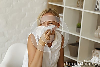 Picture of young blond sick woman blowing her nose Stock Photo