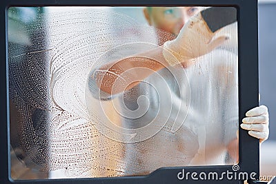 Picture of young woman cleaning fireplace glass doors Stock Photo