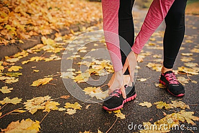 Picture of young woman stands on road and hold hands on feet. She feels pain. Woman suffer. She is alone in park. Stock Photo