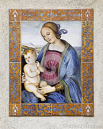 Art piece featuring the Madonna with the Child Jesus in an outside wall niche on a street in Assisi, Italyaaly. Editorial Stock Photo