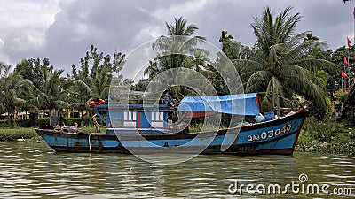 Blue working fishing boat anchored along the bank of the Thu Bon River in Hoi An, Vietnam Editorial Stock Photo