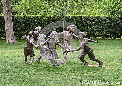 Bronze sculpture of children holding hands running in a circle by Gary Price at the Dallas Arboretum and Botanical Garden Editorial Stock Photo