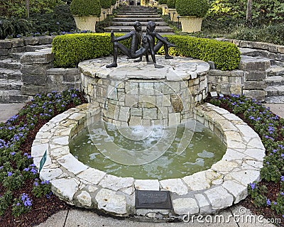 'Chico y Chica de la Playa' by Victor Salmones atop a fountain in a garden in the Dallas Arboretum. Editorial Stock Photo