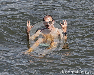 Caucasian male, husband of a Korean wife, giving the Emeka hand signal as he floats in Grand Lake, Oklahoma on July 4th, 2022. Stock Photo