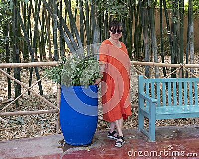 Female Korean tourist standing next to a blue pot with Ruscus aculeatus in the Jardin Majorelle in Marrakesh, Morocco. Stock Photo