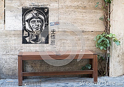 Grafitti showing a spaceman on wall above a bench on a street in Rome Editorial Stock Photo