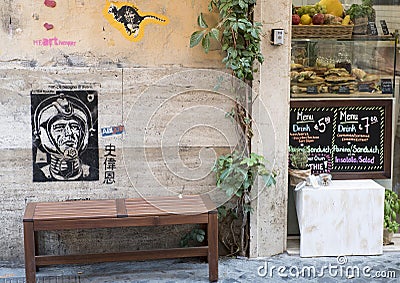 Grafitti showing a spaceman on wall above a bench on a street in Rome Editorial Stock Photo