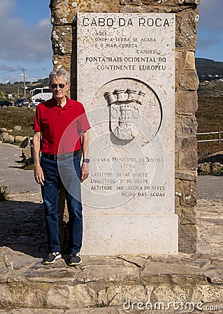 Senior male tourist by the Monument to Cabo da Roca being the westernmost point of Europe, on the Atlantic Ocean in Portugal. Editorial Stock Photo