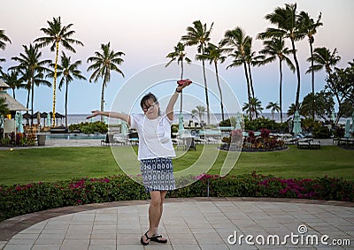 Sixty-three year-old female Korean tourist excited about the morning at a Hawaiian resort on the Big Island, Hawaii. Stock Photo