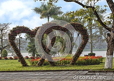 Hearts made of flowers with other red and yellow flowers and the Parfume River in the background during Tet in Hue, Vietam Stock Photo