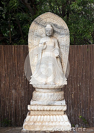 White marble statue of a standing Buddha with Abhaya Mudra on display at a resort in Maui. Stock Photo