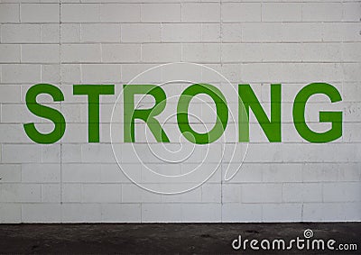 STRONG is painted in bold green letters on a white brick wall in the parking garage on Victory Park Lane, Dallas, Texas Stock Photo