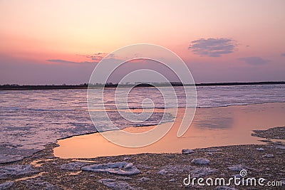 Picturesque colorful ice drift on a calm wide river during the pink sunset with pink reflection on water Stock Photo