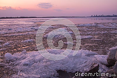 Picturesque colorful ice drift on a calm wide river during the pink sunset with pink reflection on water Stock Photo