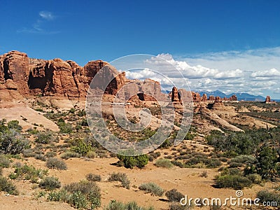 Picturesque desert scene with mountains, bushes, and clouds Stock Photo
