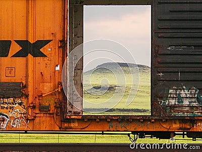 The picturesque green Texas Panhandle plateau is seen through the open doors of a rail car in morning light. Stock Photo