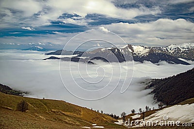 Picturesque landscape with snow-capped mountaintops and a few wispy clouds in the valley below Stock Photo