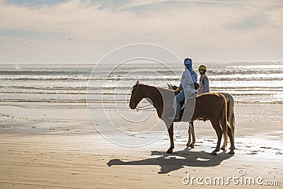 A picturesque scene of a California mounted patrol unit patrolling the sandy shores of a sunlit beach with the Pacific Ocean in Editorial Stock Photo