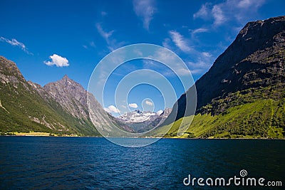 Picturesque scene of Urke village and Hjorundfjorden fjord, Norway. Drammatic sky and gloomy mountains. Landscape Stock Photo