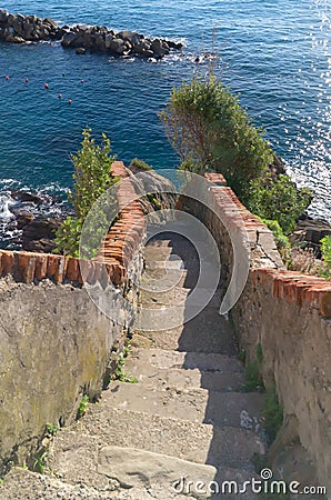 Picturesque staircase at the end of a path that reaches the sea in Riomaggiore, 5 terre. Liguria, Italy Stock Photo