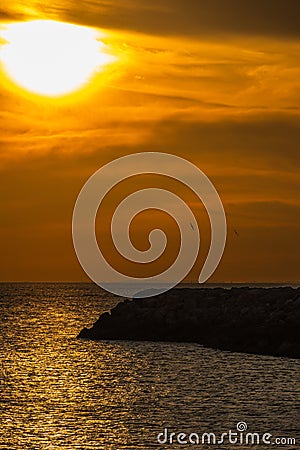 Picturesque sunset over a tranquil sea with various birds flying in the distance Stock Photo