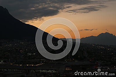 Picturesque view of sunset with dark clouds above big mountains and evening city Editorial Stock Photo